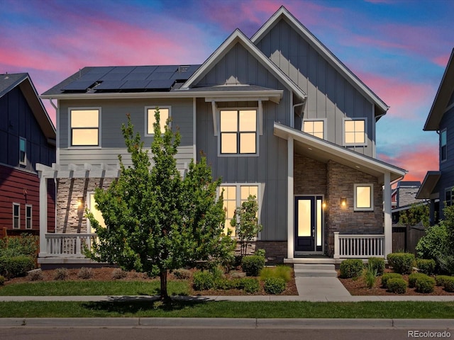 10235 E 59th Ave, Denver, CO 80238 - view of front of property featuring board and batten siding, roof mounted solar panels, and stone siding