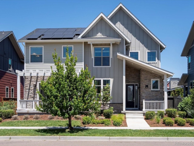 10235 E 59th Ave, Denver, CO 80238 - view of front of property featuring board and batten siding, roof mounted solar panels, stone siding, and a porch