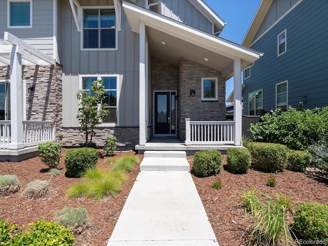 10235 E 59th Ave, Denver, CO 80238 - property entrance featuring board and batten siding, covered porch, and stone siding