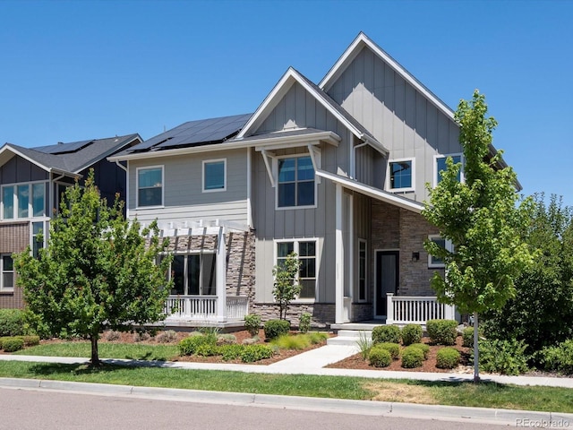 10235 E 59th Ave, Denver, CO 80238 - view of front of home featuring board and batten siding, a porch, roof mounted solar panels, and stone siding