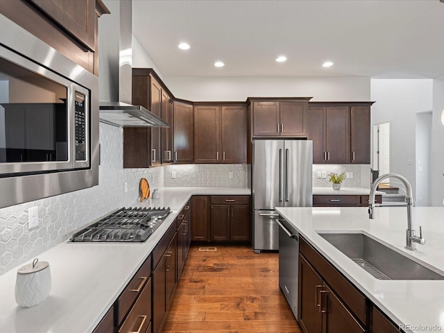 10235 E 59th Ave, Denver, CO 80238 - kitchen with appliances with stainless steel finishes, wall chimney exhaust hood, dark brown cabinetry, dark wood-type flooring, and light countertops