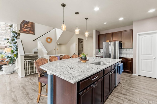 7018 E 123rd Pl, Thornton, CO 80602 - kitchen featuring appliances with stainless steel finishes, a sink, a kitchen bar, light wood-type flooring, and recessed lighting