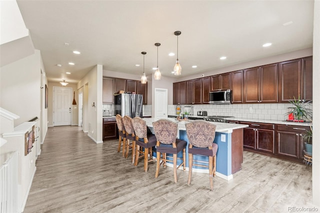 7018 E 123rd Pl, Thornton, CO 80602 - kitchen with stainless steel appliances, recessed lighting, an island with sink, light wood-style floors, and tasteful backsplash