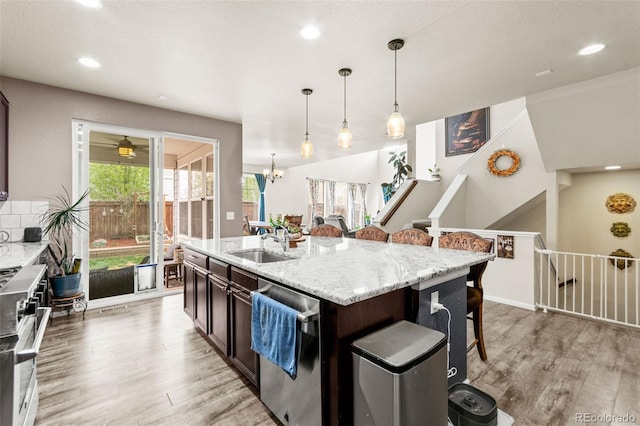 7018 E 123rd Pl, Thornton, CO 80602 - kitchen featuring stainless steel appliances, a sink, light wood-style flooring, a kitchen bar, and recessed lighting