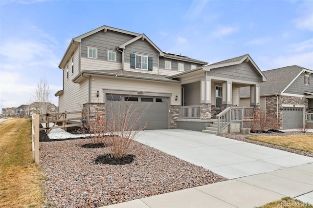 craftsman inspired home with driveway, covered porch, stone siding, and a garage