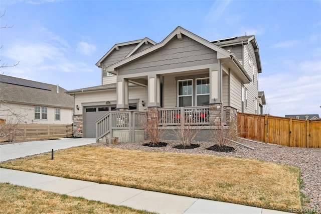 craftsman inspired home with stone siding, fence, an attached garage, driveway, and a porch