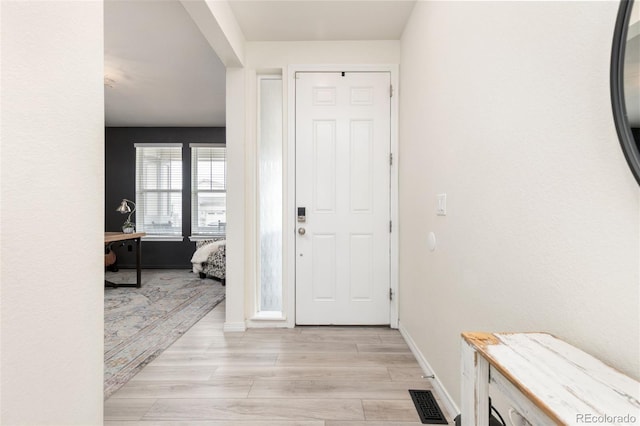 foyer with light wood-style flooring, baseboards, and visible vents