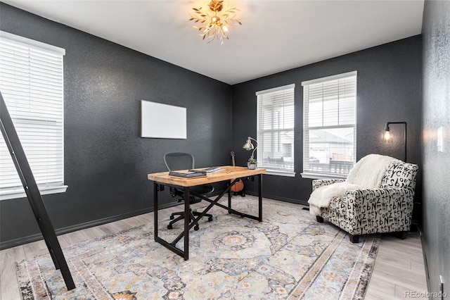 office featuring a textured wall, baseboards, and wood finished floors