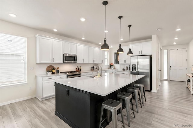 kitchen with a large island, a sink, stainless steel appliances, and white cabinets
