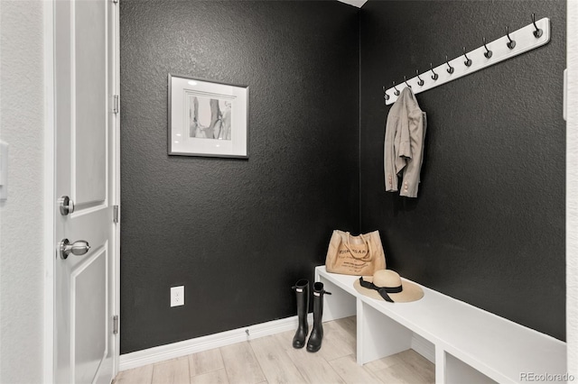 mudroom with baseboards, a textured wall, and wood finish floors
