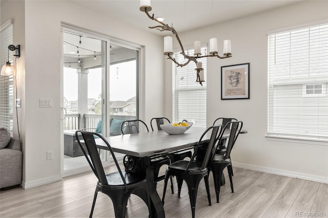 dining area with an inviting chandelier, baseboards, and light wood-type flooring