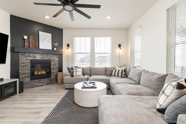 living area featuring a fireplace, a ceiling fan, light wood finished floors, and recessed lighting