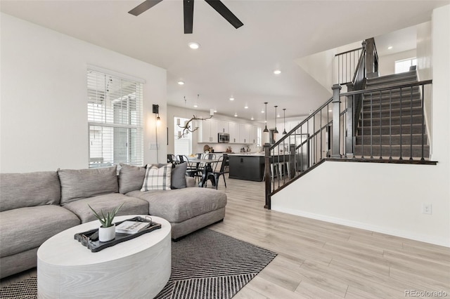 living area featuring stairs, light wood-type flooring, recessed lighting, baseboards, and ceiling fan
