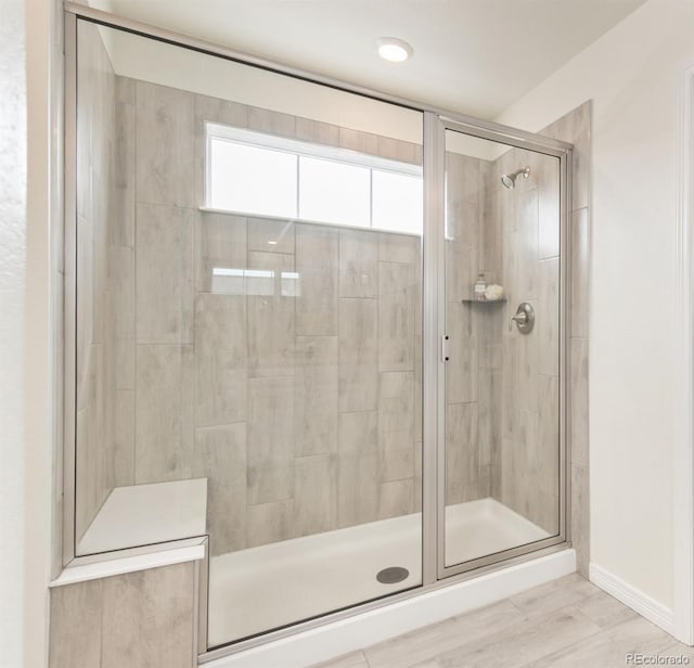 full bathroom with a shower stall and baseboards