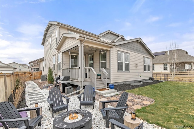 rear view of property featuring a fenced backyard, a fire pit, central AC, and a yard