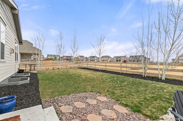 view of yard featuring a garden, fence, and a residential view