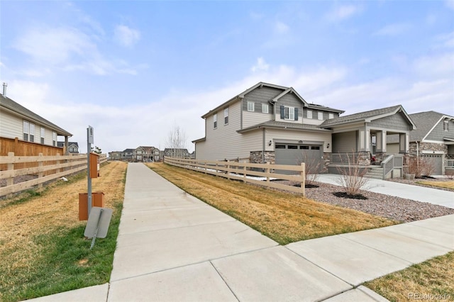 view of property exterior featuring driveway, stone siding, fence, and a garage