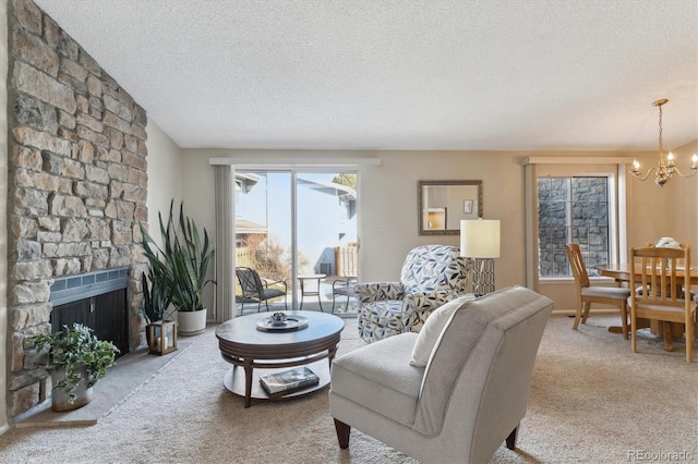 living room featuring light colored carpet, a stone fireplace, a textured ceiling, and a notable chandelier