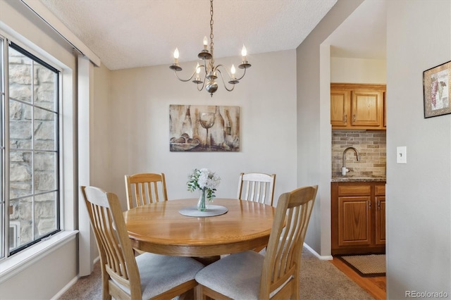 carpeted dining space featuring plenty of natural light, sink, an inviting chandelier, and a textured ceiling