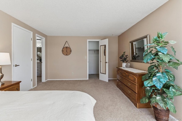 carpeted bedroom with a walk in closet and a textured ceiling