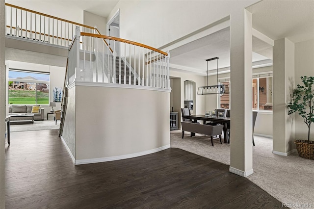 stairway with baseboards, a high ceiling, and wood finished floors