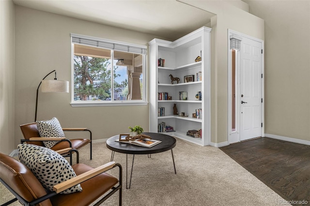 living area featuring dark colored carpet and baseboards