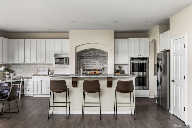 kitchen featuring white cabinets, dark wood-style floors, a breakfast bar, and stainless steel appliances