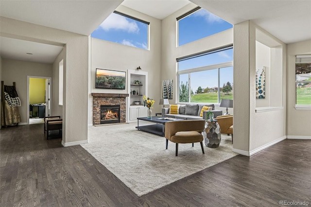 living area featuring baseboards, dark wood finished floors, a high ceiling, and a fireplace