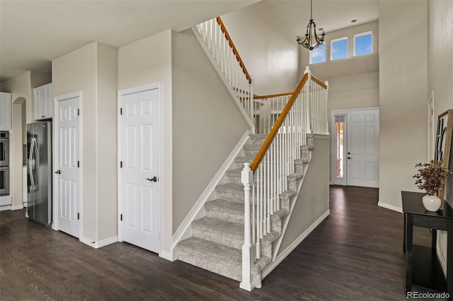 stairs with baseboards, wood finished floors, and a chandelier