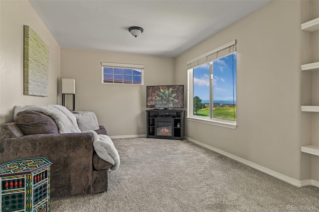 carpeted living room with a glass covered fireplace and baseboards