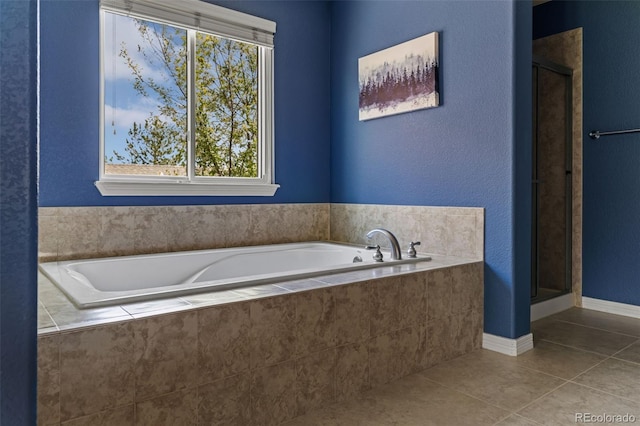 bathroom featuring a garden tub, baseboards, tile patterned floors, and a shower stall