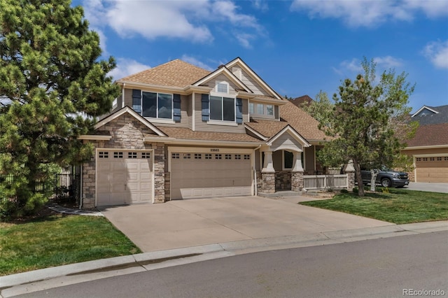 craftsman-style home featuring an attached garage, driveway, stone siding, and a front lawn