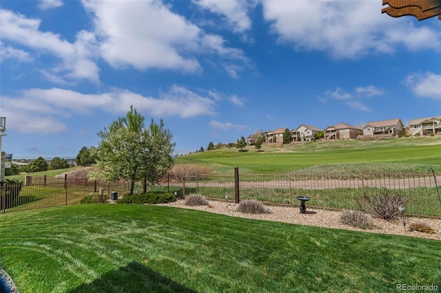 view of home's community featuring fence, a yard, and a residential view