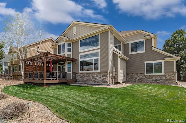rear view of house with a lawn, a deck, a pergola, and stone siding