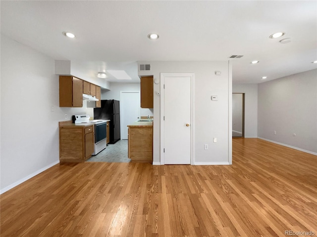 kitchen with electric stove, black fridge, sink, and light wood-type flooring