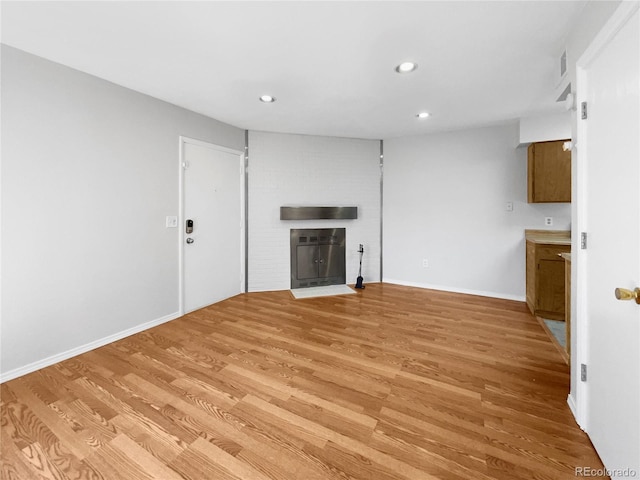 unfurnished living room featuring a fireplace and light hardwood / wood-style flooring