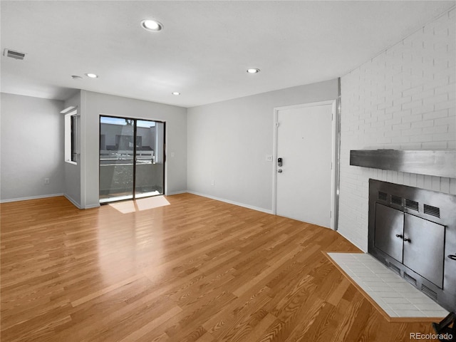 unfurnished living room featuring a brick fireplace and light hardwood / wood-style floors