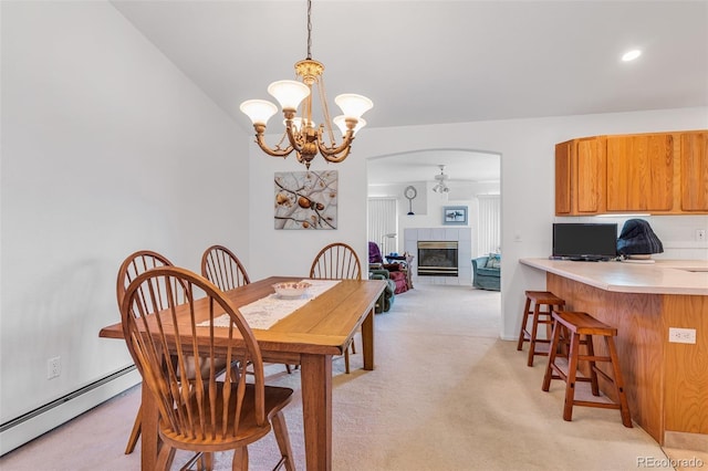 1041 Rockafellow Ct, Canon City, CO 81212 - dining space with light carpet, a baseboard heating unit, a tiled fireplace, arched walkways, and a notable chandelier