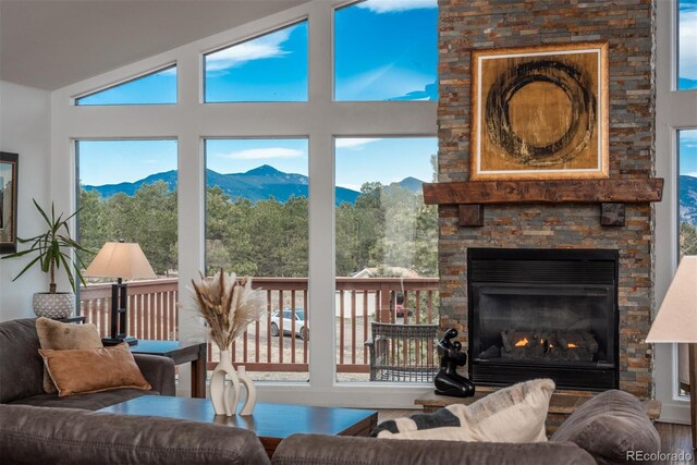 28364 Tresine Dr, Evergreen, CO 80439 - living area with a mountain view, wood finished floors, a stone fireplace, vaulted ceiling, and healthy amount of natural light