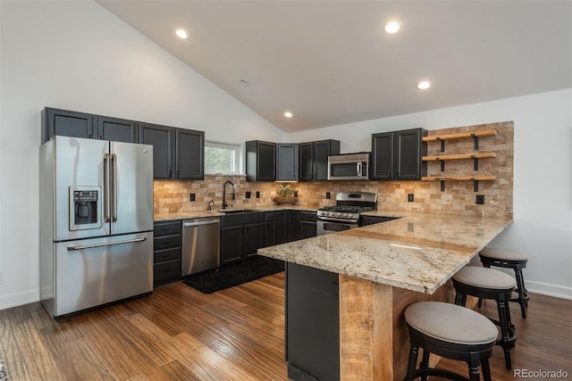 28364 Tresine Dr, Evergreen, CO 80439 - kitchen with appliances with stainless steel finishes, a peninsula, light stone countertops, a kitchen bar, and open shelves