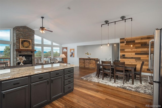 28364 Tresine Dr, Evergreen, CO 80439 - kitchen with freestanding refrigerator, a ceiling fan, dark wood-type flooring, a stone fireplace, and light stone countertops