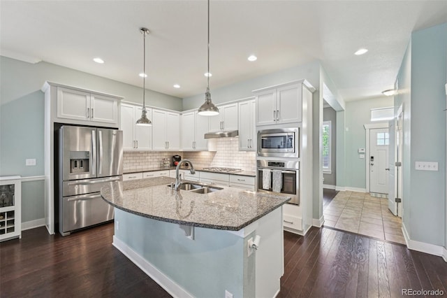 11346 E 27th Ave, Denver, CO 80238 - kitchen featuring appliances with stainless steel finishes, a sink, dark stone countertops, tasteful backsplash, and a center island with sink