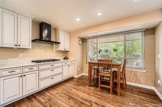 11522 Pine Grove Ln, Parker, CO 80138 - kitchen with wall chimney range hood, stainless steel gas stovetop, wood finished floors, baseboards, and recessed lighting