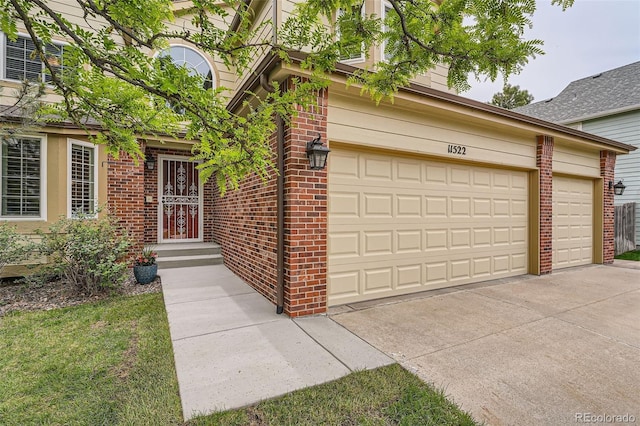 11522 Pine Grove Ln, Parker, CO 80138 - view of exterior entry featuring brick siding, a garage, and concrete driveway