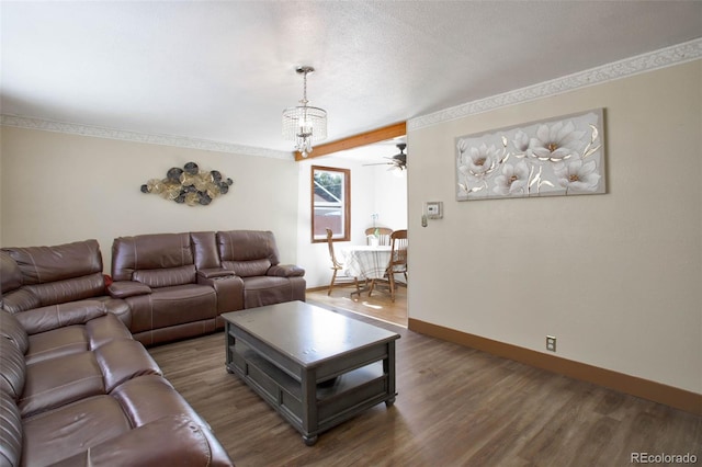 living room with a notable chandelier, a textured ceiling, baseboards, and wood finished floors