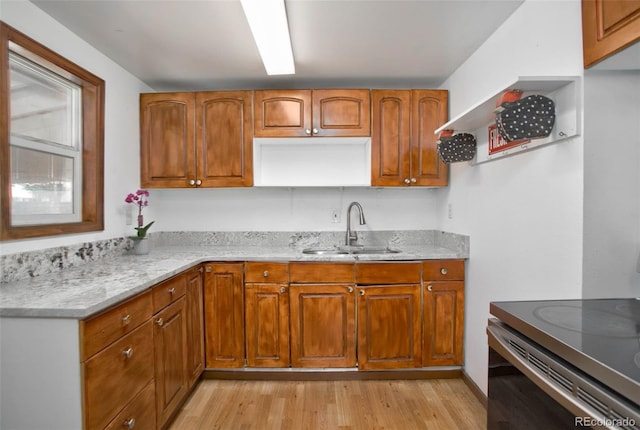 kitchen with a sink, light stone countertops, and brown cabinets