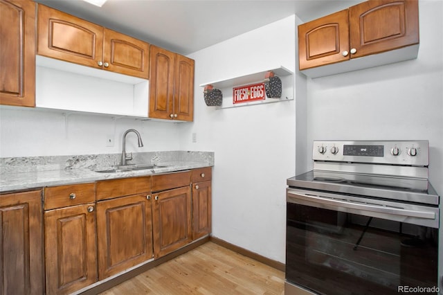 kitchen featuring light wood-type flooring, brown cabinets, a sink, stainless steel electric range oven, and light stone countertops