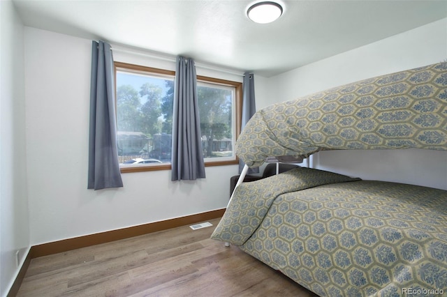 bedroom with visible vents, baseboards, and wood finished floors