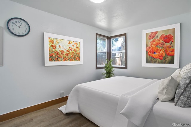 bedroom featuring wood finished floors and baseboards