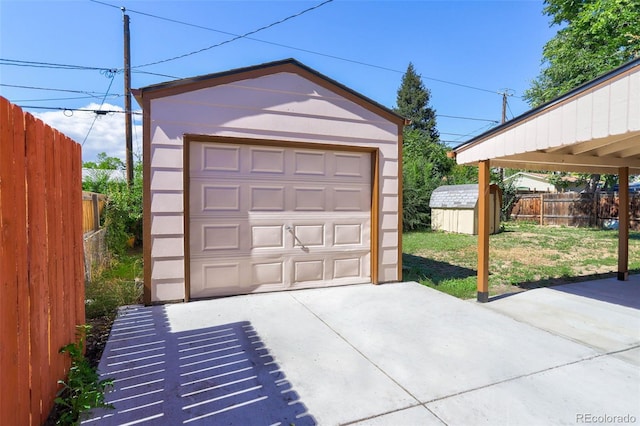 detached garage featuring concrete driveway and fence